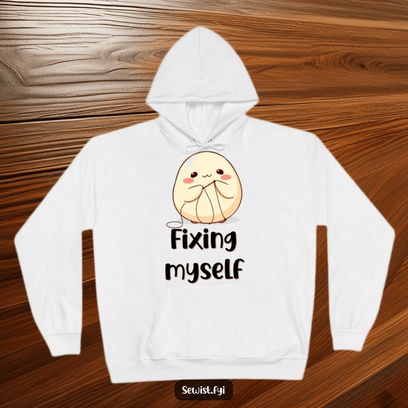 Funny hoodie illustrating a round dumpling comically attempting to stitch itself with a needle and thread.